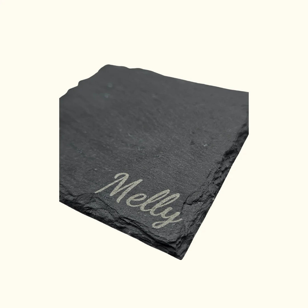 Detailansicht der Namensgravur auf dem Stein-Untersetzer; die Abbildung zeigt beispielhaft den Namen „Melly“ in eleganter Schreibschrift auf der strukturierten Schieferoberfläche