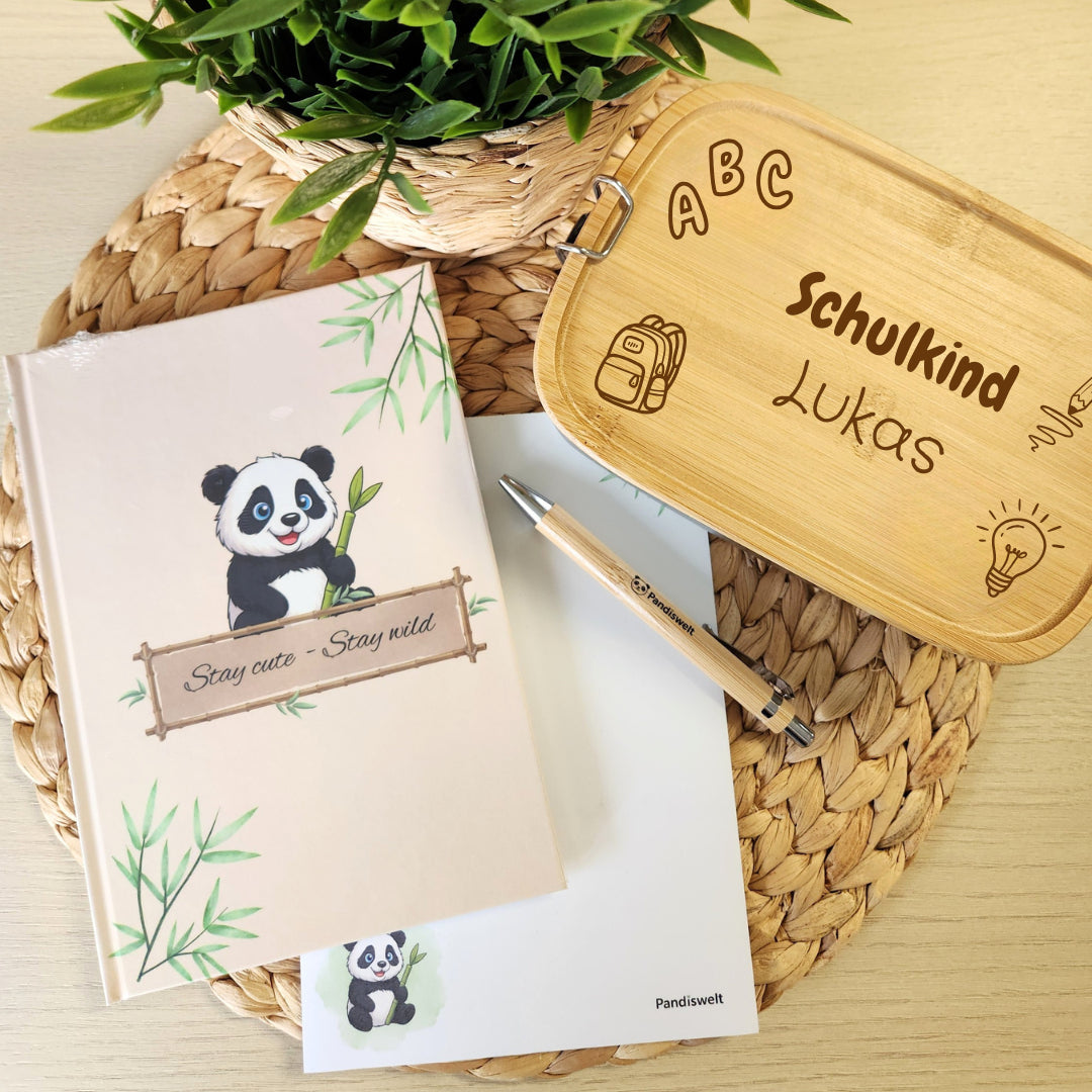 Personalisierte Brotdose mit Namensgravur "Schulkind Lukas" neben Notizbuch "Stay cute - Stay wild" und Notizblock im Panda-Design für die Einschulung