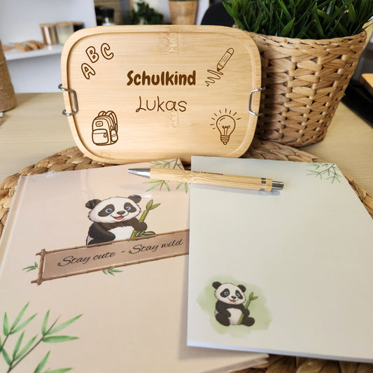 Einschulungsgeschenk-Set von Pandiswelt mit gravierter Brotdose, Panda-Notizbuch und passendem Notizblock, dekoriert auf einem Tisch