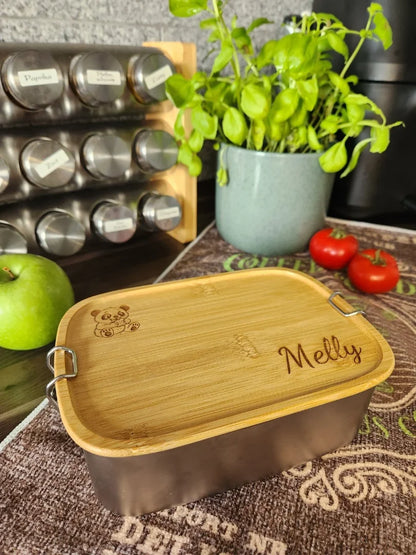 Personalisierte Edelstahl-Brotdose mit Bambusdeckel und Panda-Gravur; modern präsentiert in einer Küche neben frischen Kräutern und einem Gewürzregal als nachhaltiger Alltagsbegleiter