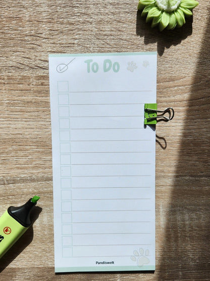 Ein schmaler Checklisten-Block mit 10 Blatt zum strukturierten Abhaken von Aufgaben; zeigt das cleane „To Do“ Design mit grünem Metall-Clip und Pfoten-Detail in natürlichem Licht auf einer Holzoberfläche
