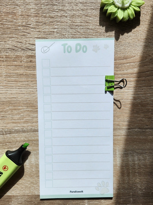 Ein schmaler Checklisten-Block mit 10 Blatt zum strukturierten Abhaken von Aufgaben; zeigt das cleane „To Do“ Design mit grünem Metall-Clip und Pfoten-Detail in natürlichem Licht auf einer Holzoberfläche