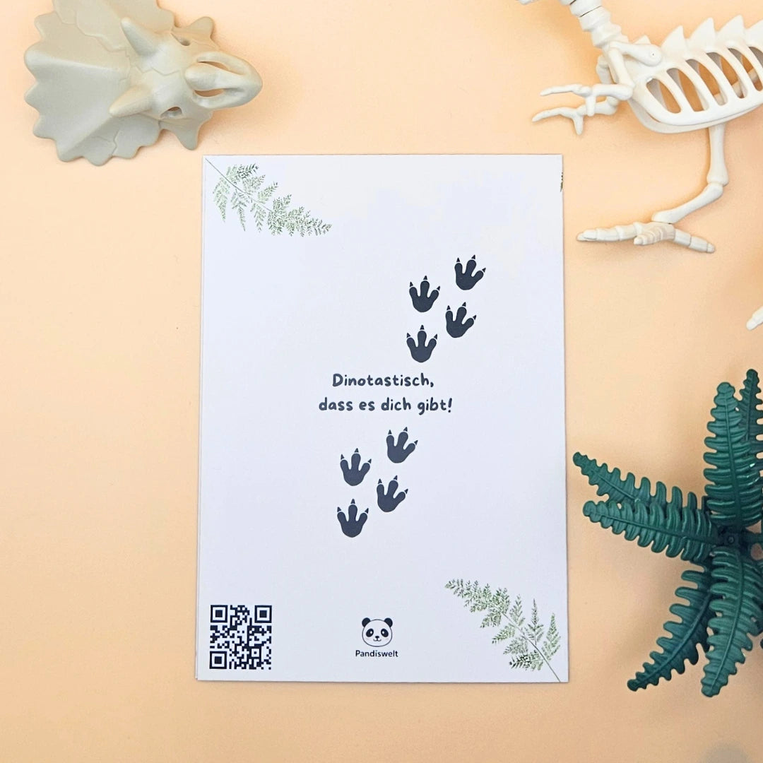 Rückseite der Karte mit dem Wortspiel „Dinotastisch, dass es dich gibt!“, Dino-Fußabdrücken und dem Pandiswelt-Markenlogo
