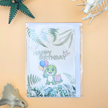 Dino-Geburtstagskarte im A6 Format inklusive weißem Umschlag und Schutzhülle, präsentiert in einer dekorativen Urzeit-Kulisse mit Dino-Skeletten
