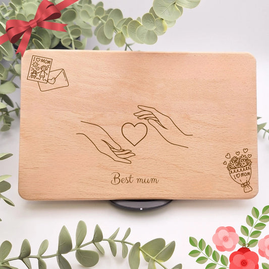 Frühstücksbrett aus Holz mit zwei gravierten Händen, einem Herz dazwischen und dem Schriftzug Best Mum, ergänzt durch Brief und Blumenstrauß