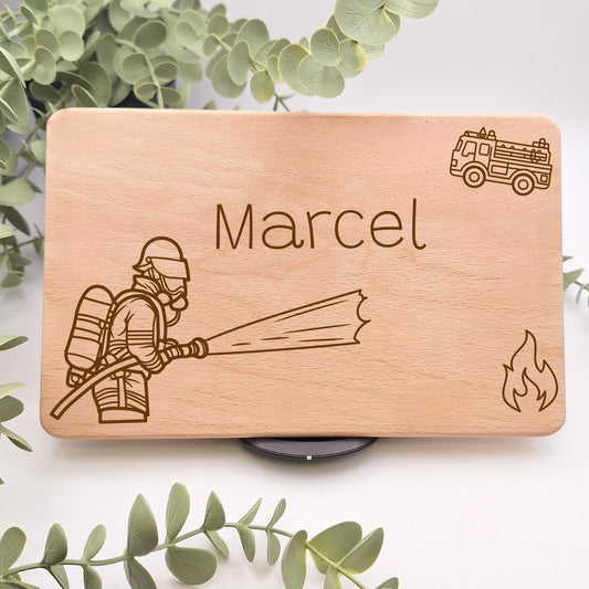 Frühstücksbrett aus Buchenholz personalisiert mit einem Namen beispielsweise Marcel und drei Feuerwehr Motiven darunter ein Feuerwehrmann mit Schlauch, ein Feuerwehr Auto und einem Feuer