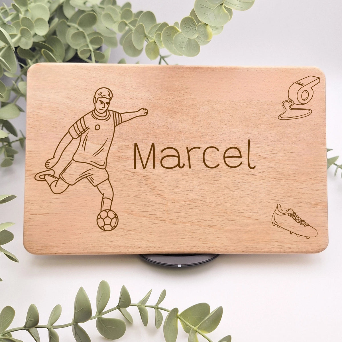 Personalisiertes Frühstücksbrett mit Namen beispielsweise Marcel und drei Fußballmotiven. Darunter ein Fußballspieler mit einem Ball am Fuß, eine Trillerpfeife und Fußballschuhe