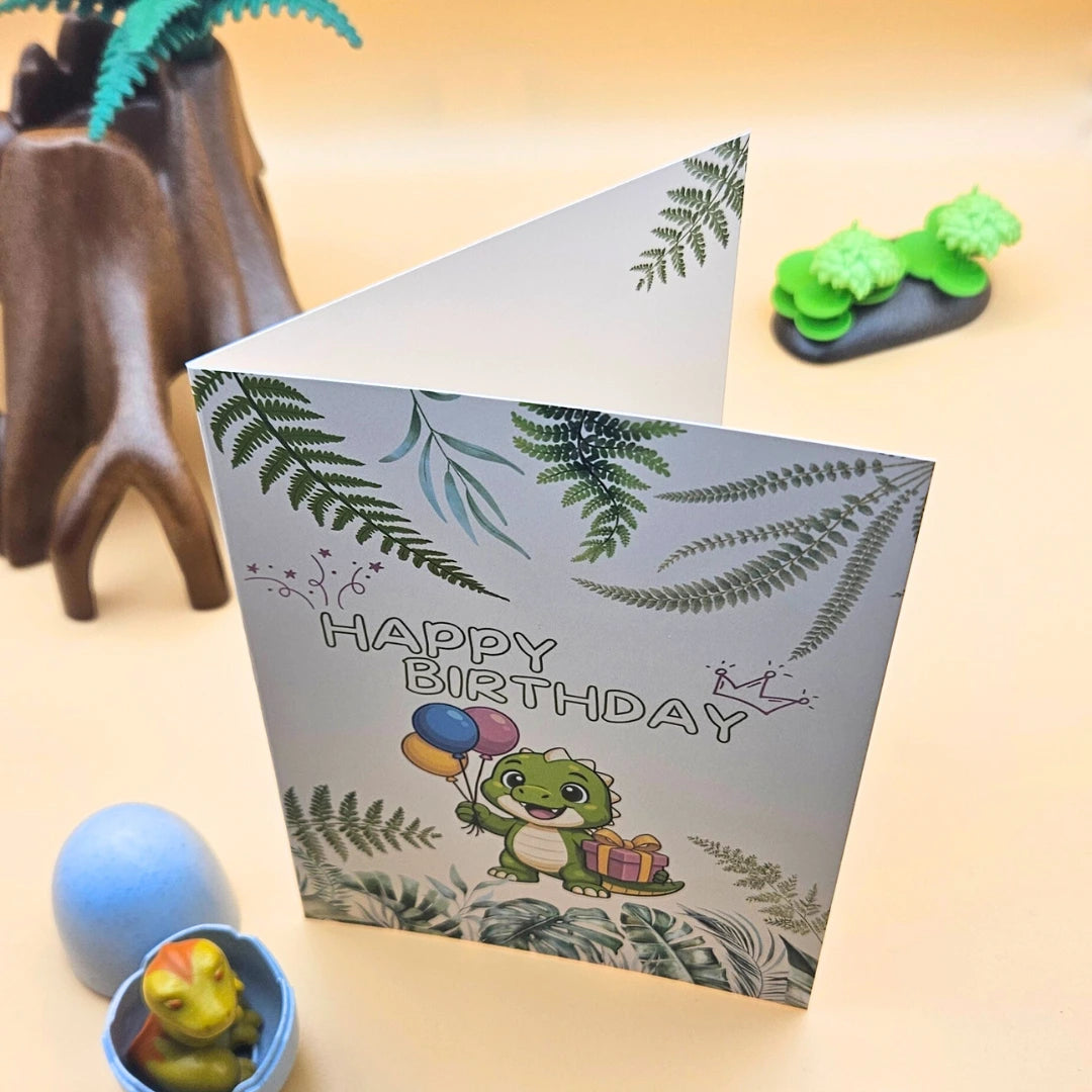 Schräg stehende Dino-Klappkarte zur Verdeutlichung der Papierqualität, modern inszeniert in einer Spielzeug-Dinosaurier-Landschaft