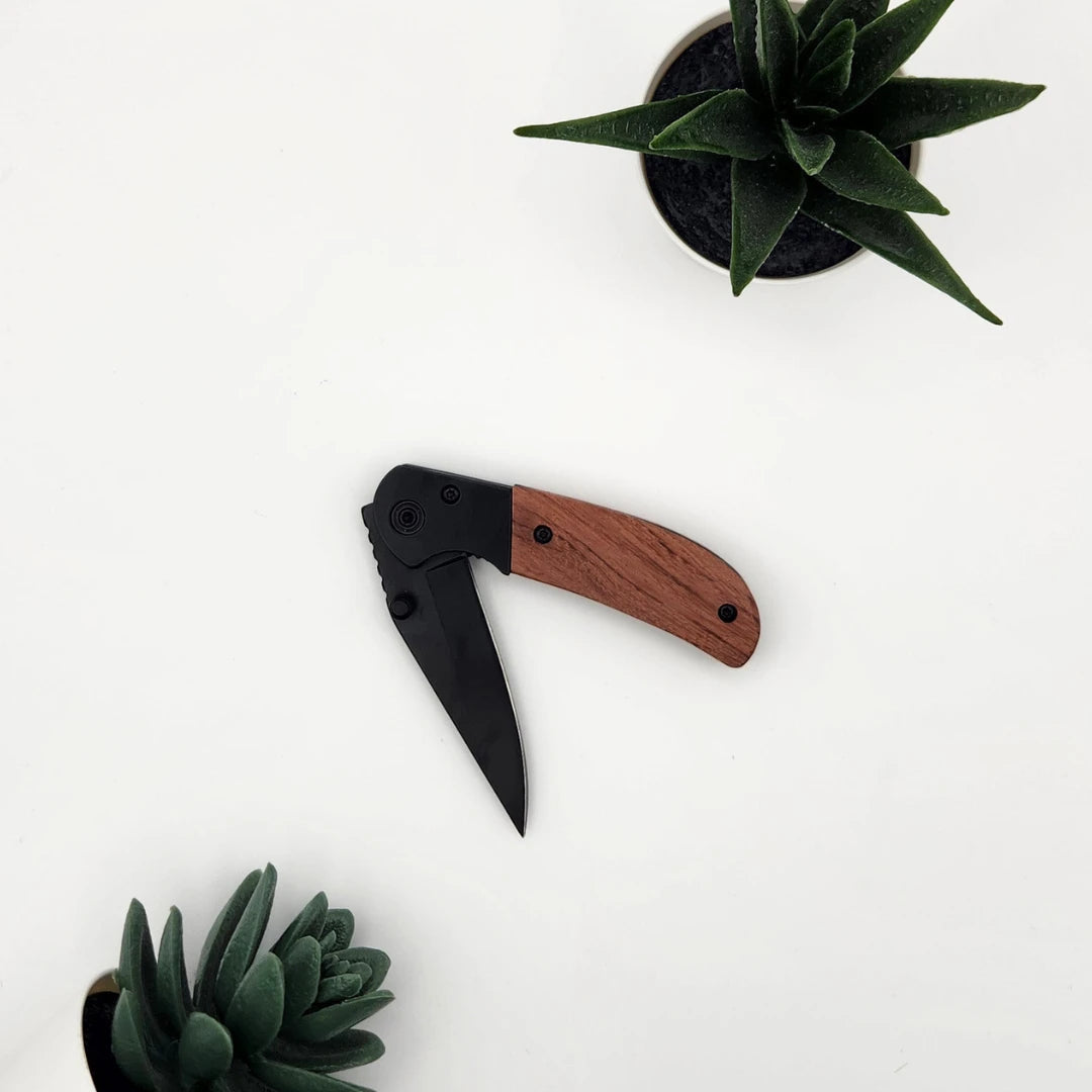 Halb geöffnetes Klappmesser mit schwarzer Klinge und rotbraunem Holzgriff von oben fotografiert