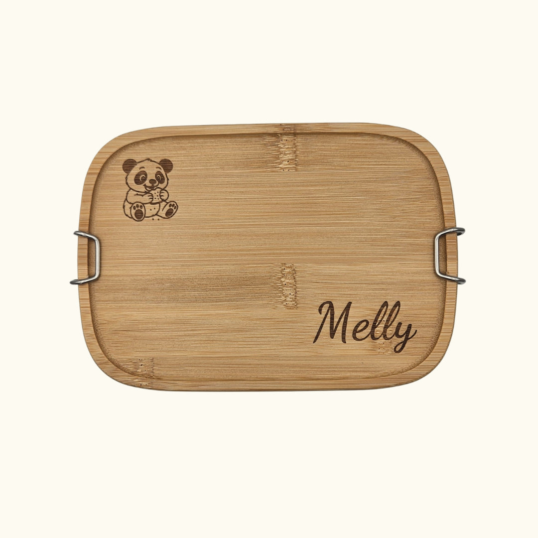 Detailreiche Draufsicht auf den personalisierbaren Bambusdeckel der Brotdose; hochwertige Lasergravur eines Pandas und des Namens „Melly“ auf natürlichem Holz