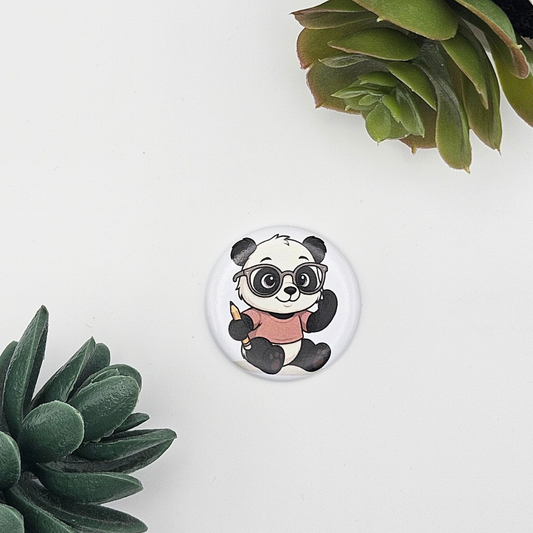 Runder Magnet (3,8 cm) mit einem niedlichen Panda, der eine Brille trägt und einen Stift hält; ästhetisch präsentiert auf weißem Grund zwischen grünen Sukkulenten, passend als Geschenk für Lehrer oder Schüler
