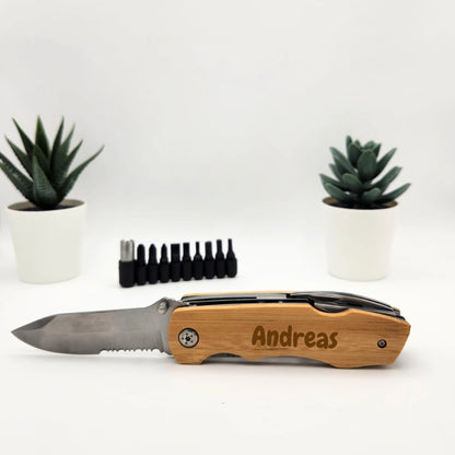 Multitool aus Bambus mit aufgeklapptem Messer und der Gravur Andreas ohne Motiv, dahinter das Bit-Set