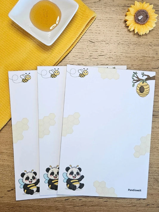 Ansicht des A5 Notizblocks mit niedlichem Panda-Bienen-Motiv und illustrierten Honigwaben; die Darstellung zeigt das Layout des Blocks, dekoriert mit echtem Honig und einer Sonnenblumen-Kerze in einer sonnengelben Farbwelt