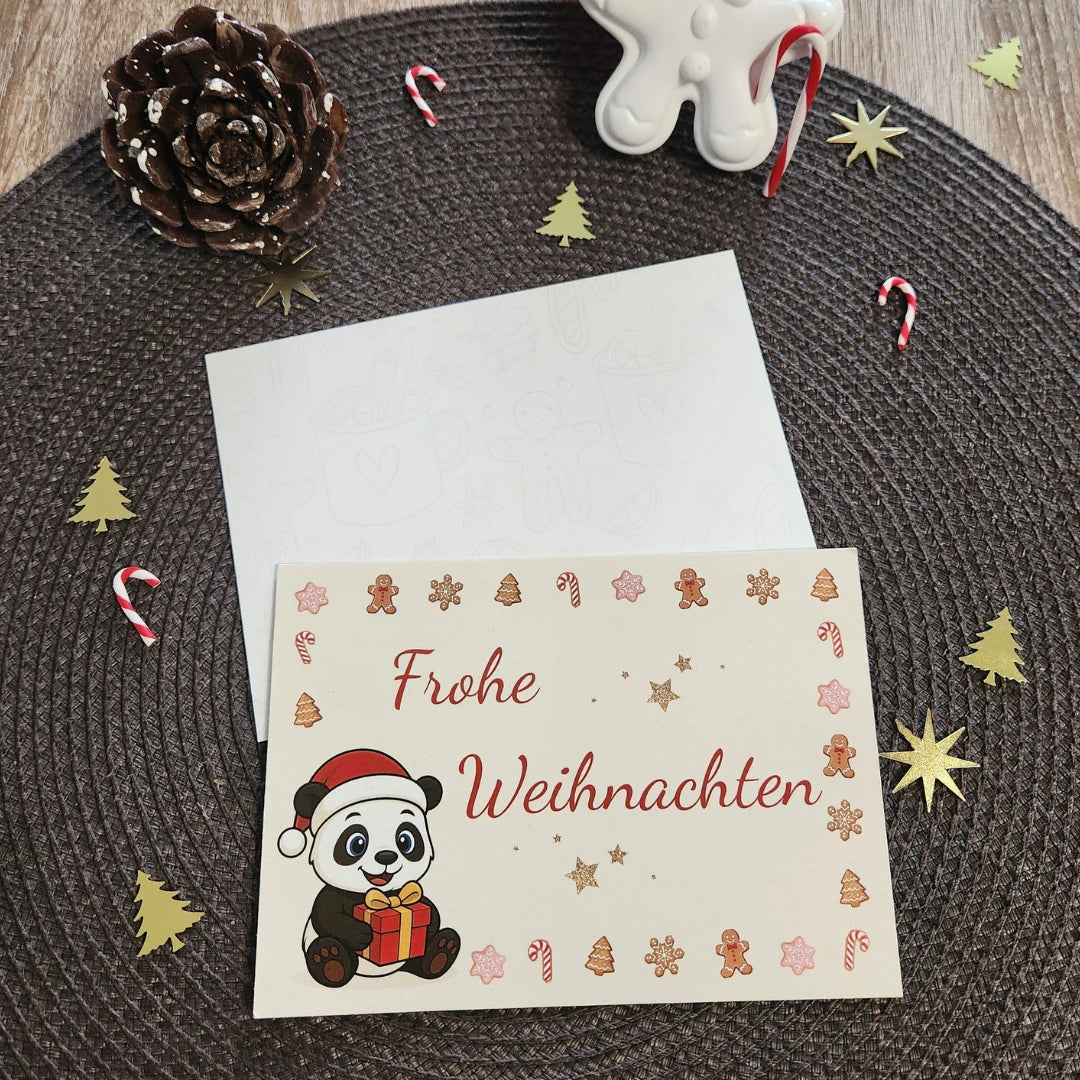 Einzelne Panda-Weihnachtskarte im A6-Format mit dem Motiv „Panda mit Geschenk“ und dem Schriftzug „Frohe Weihnachten“ in festlicher Dekoration