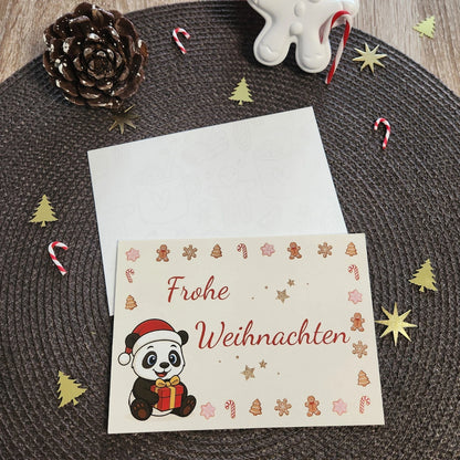 Einzelne Panda-Weihnachtskarte im A6-Format mit dem Motiv „Panda mit Geschenk“ und dem Schriftzug „Frohe Weihnachten“ in festlicher Dekoration