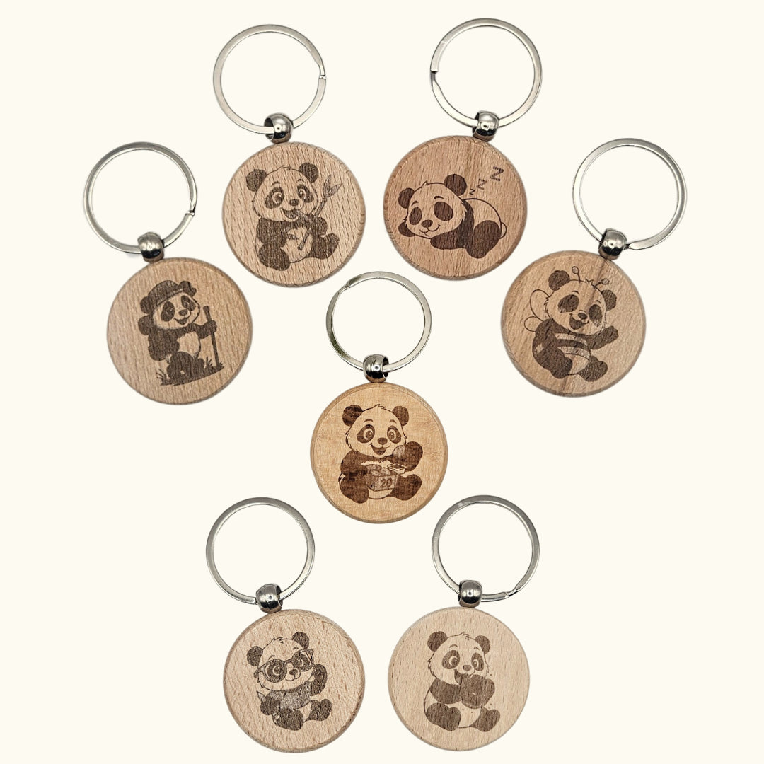 Übersicht von sieben verschiedenen Panda-Motiven für den runden 4 cm Buchenholz-Schlüsselanhänger; zeigt Designs wie den Donut-Panda, Wanderer, Biene und den Panda mit Brille zur freien Auswahl