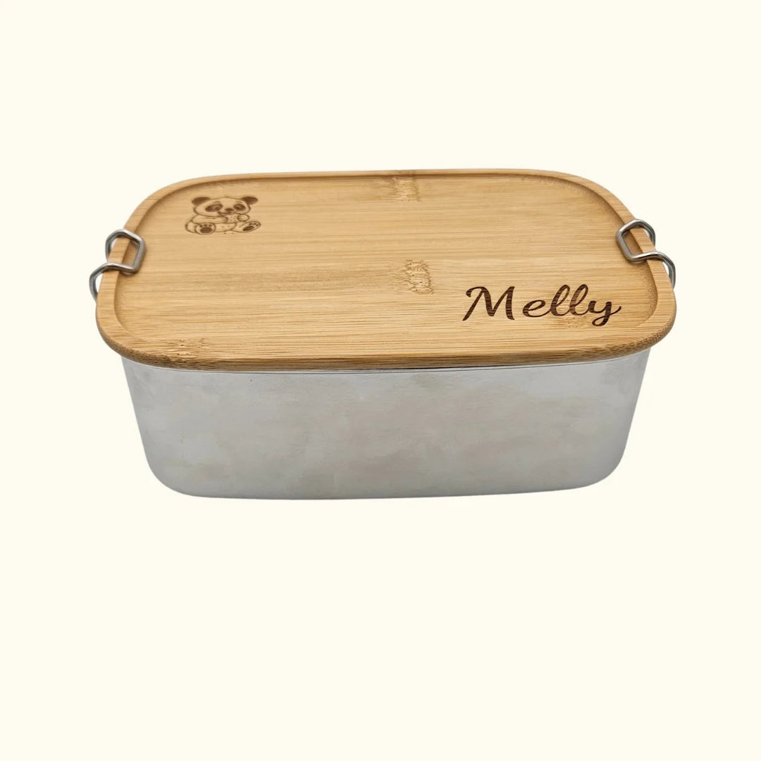 Geschlossene Edelstahl-Brotdose mit laser-graviertem Bambusdeckel; das Design zeigt beispielhaft den Namen „Melly“ und einen niedlichen Panda, präsentiert auf neutralem hellem Hintergrund