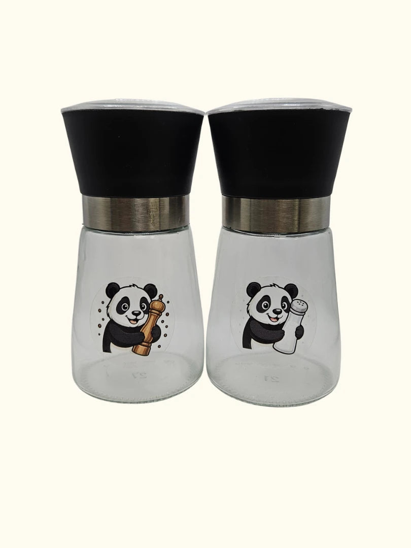 Set aus zwei Gewürzmühlen aus Glas mit schwarzen Mahlkappen und Panda-Illustrationen für Salz und Pfeffer; hochwertiges Küchenduo in modernem Design auf hellem Hintergrund
