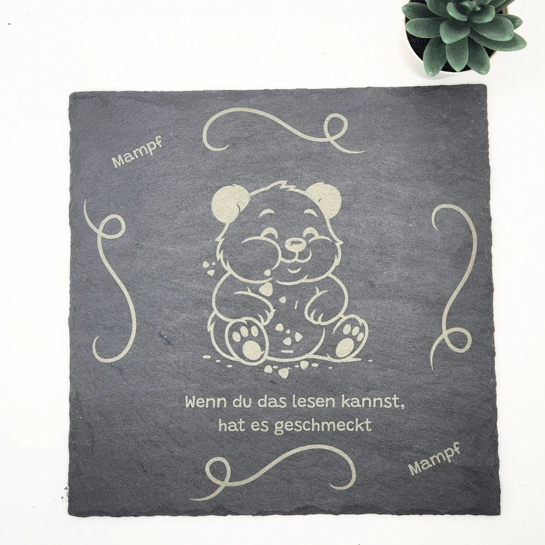 Quadratische Schieferplatte (25x25 cm) mit Panda-Illustration und dekorativen Ornamenten, zeigt den Schriftzug „Mampf“ und einen humorvollen Text in der Draufsicht