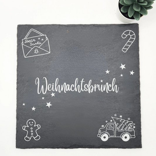 Servierplatte aus Schiefer mit dem Schriftzug Weihnachtsbrunch, einem Brief an Santa, einer Zuckerstange, einem Lebkuchenmann und einem Pick-up mit Tannenbaum