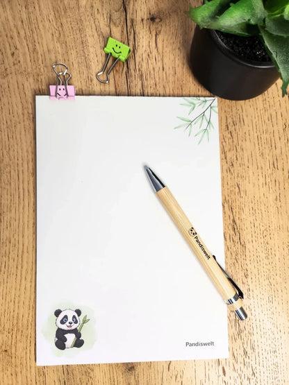 Einzelner Notizblock im Format A5 mit hochwertigem Panda-Druck und Bambuszweig; gezeigt mit einem Marken-Kugelschreiber aus Bambus in natürlichem Licht als umweltfreundliche Geschenkidee