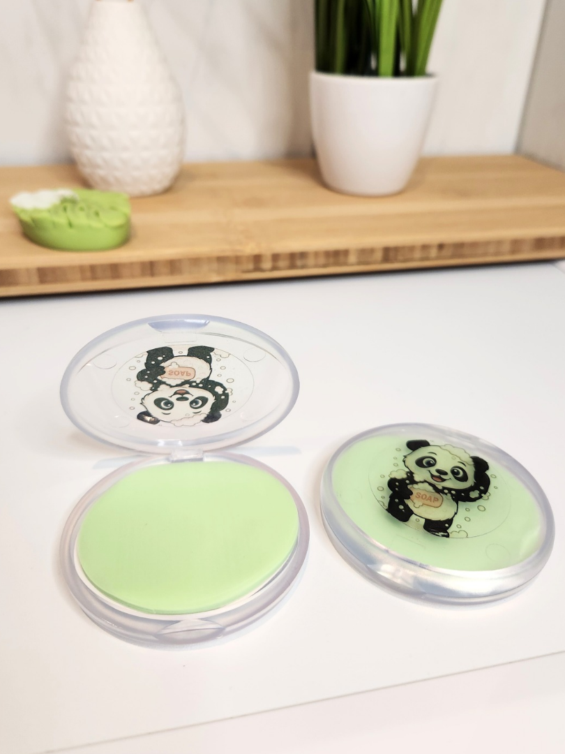 Zwei transparente Boxen mit Panda-Motiv auf einer Badezimmerablage, eine davon geöffnet mit Blick auf den Inhalt von 30 grünen Seifenblättern