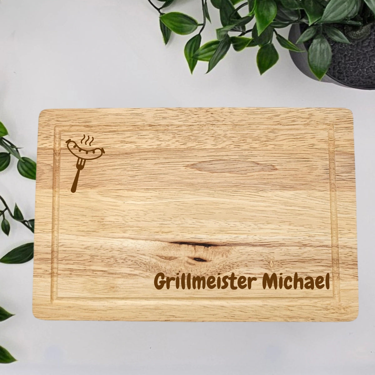Personalisiertes Steakbrett aus einem 5-teiligen Grillset mit Namen und dem Text "Grillmeister" vor dem Namen. Sowie ein Bratwurst Motiv oben links 