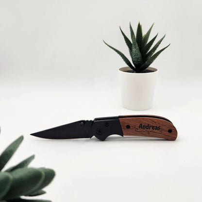Taschenmesser mit Holzgriff und Gravur Andreas, aufgeklappt neben einer Sukkulente im weißen Topf