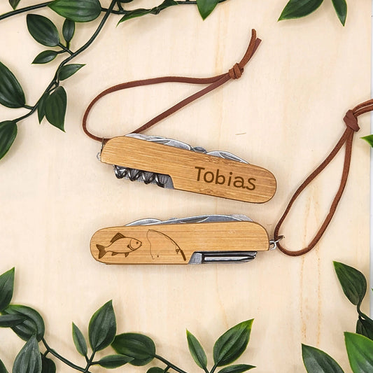Personalisiertes Taschenmesser für Leute die gerne angeln gehen mit beidseitiger Gravur. Vorderseite ein Angelmotiv aus einer Angel und einem Fisch und auf der Rückseite der Name wie beispielsweise "Tobias"